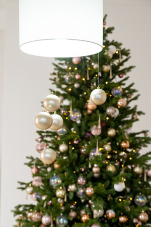 Big beautiful christmas tree decorated with beautiful shiny baubles and many different presents on wooden floor. White wall background with copy space.の写真素材