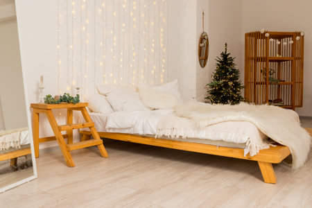 Christmas decorated bedroom interior with comfortable bed, Christmas fir tree and gift boxes on floor, copy space. Cozy home moment. Happy New Year. christmas garland lights at homeの写真素材