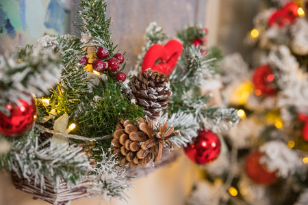 Christmas tree branches on blurred background with red balls and golden decor, berries, garland, cone. Christmas snowy fir tree branches, pine cone. Home decoration, winter holidaysの写真素材