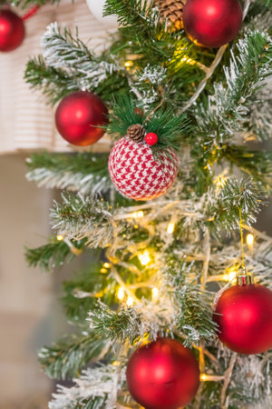 Christmas tree branches on blurred background with red balls and golden decor, berries, garland, cone. Christmas snowy fir tree branches, pine cone. Home decoration, winter holidaysの写真素材