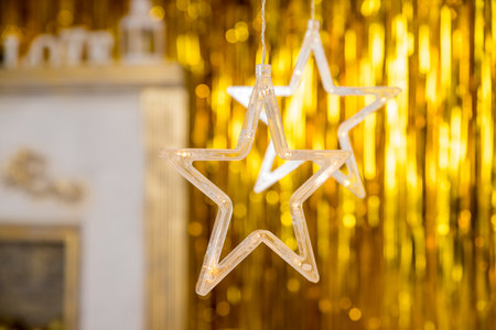 Christmas gold garland on blurred festive background. Happy New Years card.Christmas season, glass lanterns, star hanging in living room as decoration.の写真素材