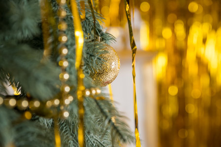 Christmas tree with golden tinsel, New Year home decorations, golden baubles, traditional celebration. Copy space. cozy home interior.New Years winter holidays.の写真素材