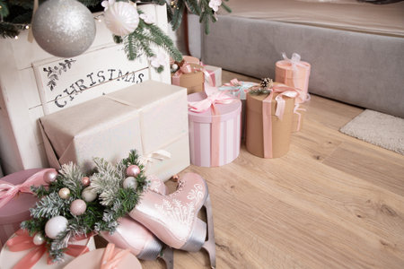 Beautiful Christmas gift boxes on floor near fir tree in room.new year cozy home interior with christmas tree and garlands. winter holidays background with presents and decorationsの写真素材