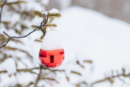 red christmas baubles hang on snowy fir branches outdoor. festive street decor. Christmas postcard with red ball on snowy Spruce branch. copy spaceの写真素材
