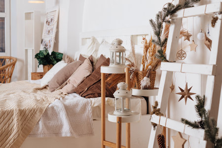cozy New Years decor of the room lit by the magic garland lights. Festive atmosphere before holidays. Scandinavian style. Loft interior with bed with white and grey cushions and wooden shelvesの写真素材