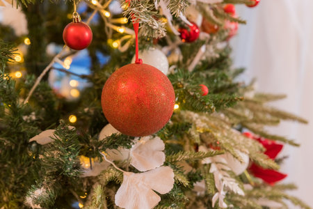 Christmas decorations on the branches fir, sparkling and fairy background. Red and white New Years Christmas ornaments on the tree, glass balls and garlands in the house.の写真素材