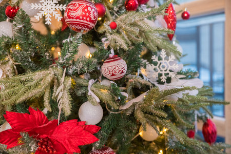 Christmas decorations on the branches fir, sparkling and fairy background. Red and white New Years Christmas ornaments on the tree, glass balls and garlands in the house.の写真素材