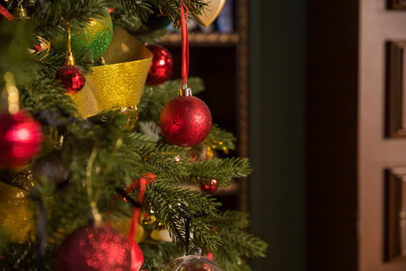Stylish Christmas minimalist interior. Comfort home with fireplace. Gifts boxes under Christmas tree with decorations red balls in dark living room. Festive atmosphereの写真素材