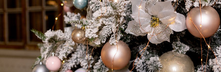 Artificial Christmas tree in a bright interior with silver, pink, bronze balls and snow on the branches. The concept of New year and Christmas. Luxury Christmas tree with glowing garland.web bannerの写真素材