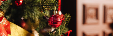 Stylish Christmas minimalist interior. Comfort home with fireplace. Gifts boxes under Christmas tree with decorations red balls in dark living room. Festive atmosphere. web bannerの写真素材
