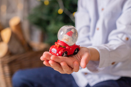 Beautiful snow globe with santa claus and snowflakes inside the sphere in the child hands, christmas decoration gift close up. winter holidays moodの写真素材