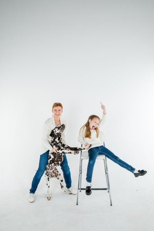 woman and toddler girl play with dog puppy dalmatian.pet and child ,generation therapy ,canisterapie,emotion, mental health. people hugging and kissing a dog, playing with puppy on a white backgroundの写真素材