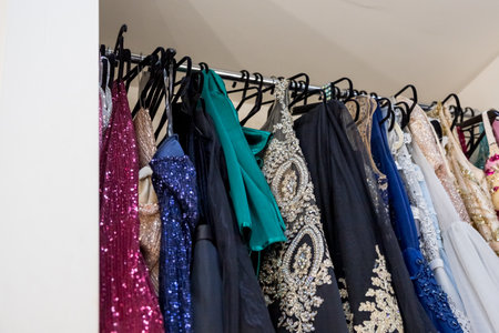 Different evening gown dresses on hangers in boutique. Pink, blue and gray sequined luxury dresses for woman hang on hangers.Row of different beautiful cloth.dress rent shopの写真素材