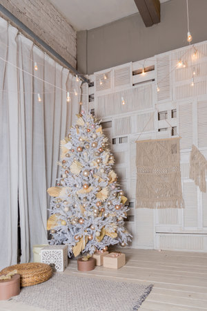 snow-covered Christmas tree with white, golden, bronze decorations and lights. Cozy Christmas tree and gift boxes in interior.Brightly lit christmas tree with lots of gifts.New year greeting card.の写真素材