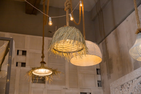 Decorating hanging lantern made from bamboo. rattan chandeliers different forms on wooden wall background. Straw lampshade in cozy living room. Eco-friendly interior design using natural materials.の写真素材