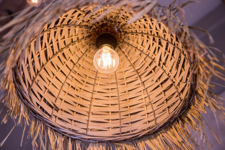 Decorating hanging lantern made from bamboo. rattan chandeliers different forms on wooden wall background. Straw lampshade in cozy living room. Eco-friendly interior design using natural materials.の写真素材