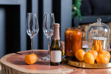 Two glasses of champagne and tangerines on a table against blurred black background. New year celebration party.Winter holidays celebrationの写真素材