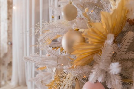 Close up of beautiful white fir branches with shiny golden, silver and white baubles or balls, shiny ornaments and garland lights, home Decoration.Festive new 2024 yearの写真素材