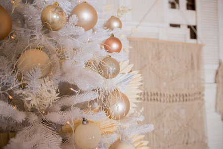 Close up of beautiful white fir branches with shiny golden, silver and white baubles or balls, shiny ornaments and garland lights, home Decoration.Festive new 2024 yearの写真素材