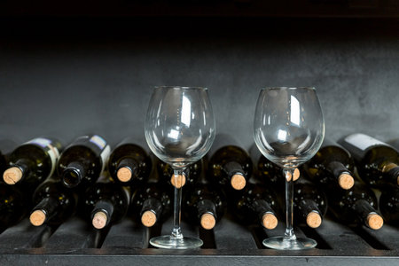 Many wine bottle and wine glasses in front of black wall. Wine tasting in the winery.copy space. different types of wine with a wine cellarの写真素材