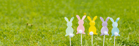 Easter bunnies cut out of colored paper are on green grass background. Easter holiday concept, childrens crafts.web banner. copy space.Creative easter compositionの写真素材