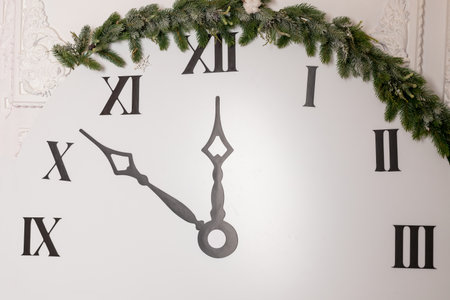 Layout clock. Dial with Roman numerals. Textured brown planks wood base. Black hands of the clock show the time - seven minutes to twelve. New Year holiday concept.の写真素材