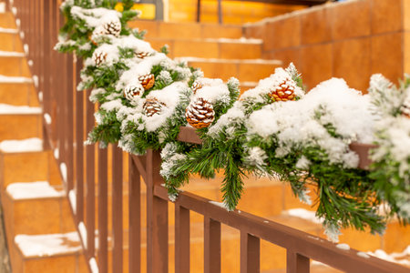 Christmas street decor under the snow. railing of the stairs are decorated with fir branches and decorative cones.Staircase decoration for the New Year. Selective focusの写真素材
