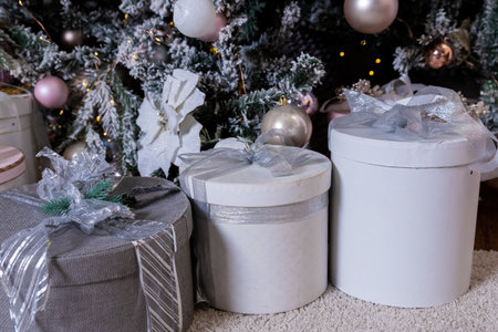 Stylish bright interior of living room with beautiful fluffy Christmas tree and gifts under it in gray and pink, Christmas and New Year celebration. Winter holidays surpriseの写真素材
