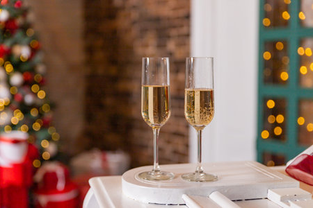 New year time party in home interior with christmas tree. Two champagne glass and desk of free space for your decoration. Winter cold day. Flutes of champagne in holiday setting.の写真素材