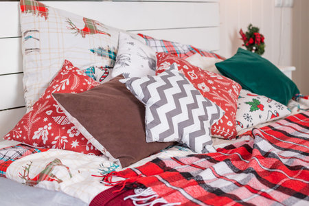 Winter Christmas home decor. Festive cozy bedroom with bed and colorful red pillows. Concept new...