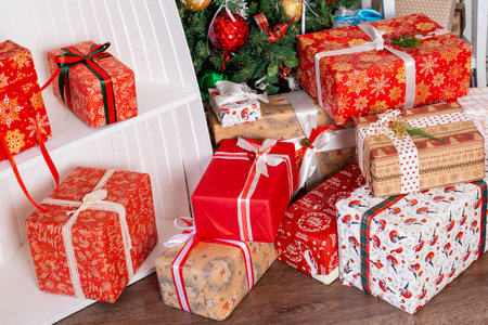 Stylish wrapped christmas gifts with ribbon near decorated christmas tree with vintage baubles and festive lights. Many present boxesの写真素材