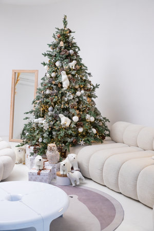 white Sofa and Decorated Christmas Pine Trees. Presents under Conifer, Teddy Bear, Pillows on Luxury Couch, Cozy Interior with Decor Holiday Elements. festive childrens photo zoneの写真素材