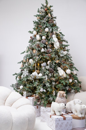 white Sofa and Decorated Christmas Pine Trees. Presents under Conifer, Teddy Bear, Pillows on Luxury Couch, Cozy Interior with Decor Holiday Elements. festive childrens photo zoneの写真素材