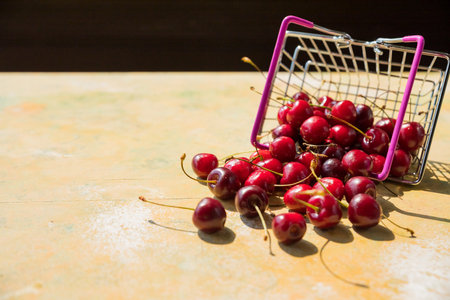 Miniature shopping basket with fresh organic ripe cherries isolated on a yellow background. Purchase of products. Agricultural products and harvesting. Organic food.GMO-free, farm market.の写真素材