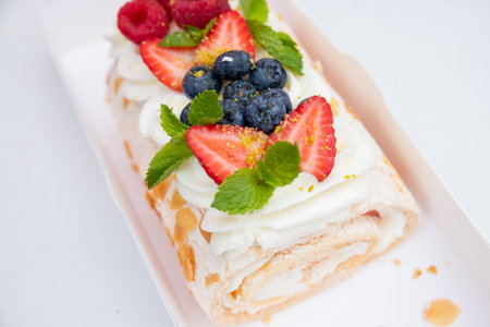 Tasty roll cake stuffed with cream cheese ,decorated with fresh strawberry, berries. Homemade shortcake cake roll with cream cheese whipped cream, perfect summer season dessert. meringue rollの写真素材