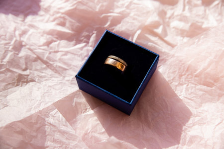 Engagement ring in blue gift box on pink background. Romantic gift idea. wedding ring artistically...