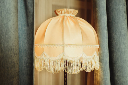 beautiful Lampshade in bedroom.old floor lamp with a hole with a fringe.Room decoration in retro style, furniture details and old lamps by the window.Vintage floor lampの写真素材