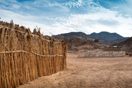 Desert in Egypt. Fence lining a house. Mountains in the Background. Cloudy sky.のeditorial素材