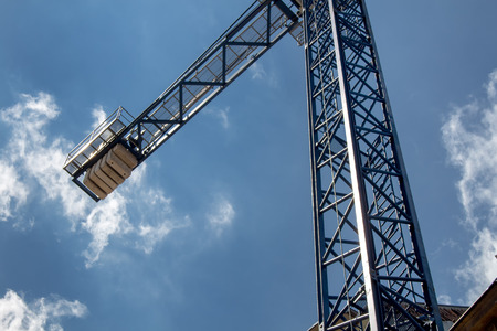 Detail of a crane with a background of a bright blue sky with small clouds.の写真素材