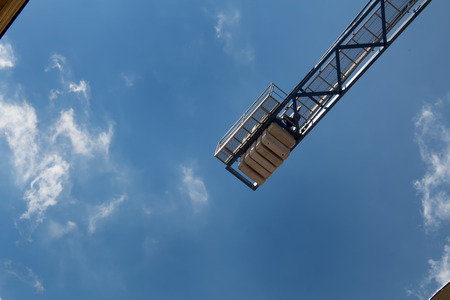 Detail of a crane with a background of a bright blue sky with small clouds.の写真素材