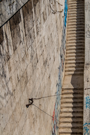 Long staircase from the Tiber riverbank to the promenade. Made of stone. High wall on the left side with graffiti.の写真素材