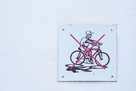 White wall with a board informing, bicycles entrance is forbidden.の写真素材