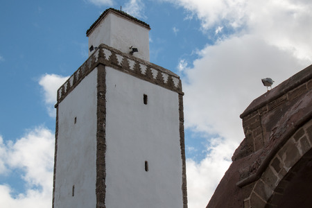 White facade of a mosque with bricks lining of the minaret. Cloudy sky.の写真素材