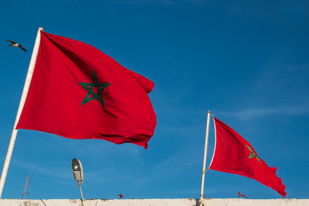 Two morrocan flags blowing in the wind. Blue sky.の写真素材