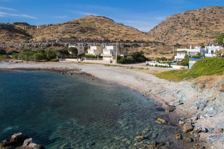 Beach with a clear water of Aegean sea, close to Athens. Small village with white houses. Mountains in the background. Blue sky, some clouds.の写真素材