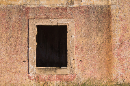 Weathered facade of an abandoned house with a built frame for the window, already without a wooden frame and glass.の写真素材