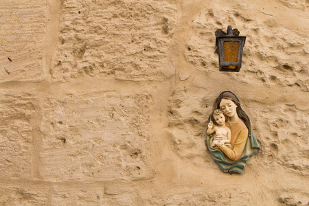 Small statue of Virgin Mary and a Child under a lantern on a texture wall of a house at the mediterranean island Malta.の写真素材
