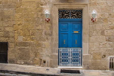 Bright blue door - entrance to an old stone house. Decorative lanterns with the maltese cross base. Seglea, island Malta.の写真素材