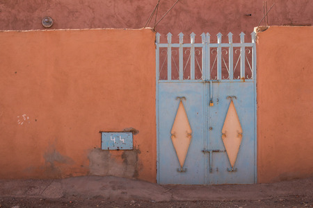 Orange fence with an enlightened blue iron gate. Photo taken in Morocco.の写真素材