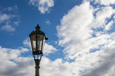 Detail of a traditional street lamp - lantern. Blue sky with many white clouds in the background. Prague, Czech republicの写真素材
